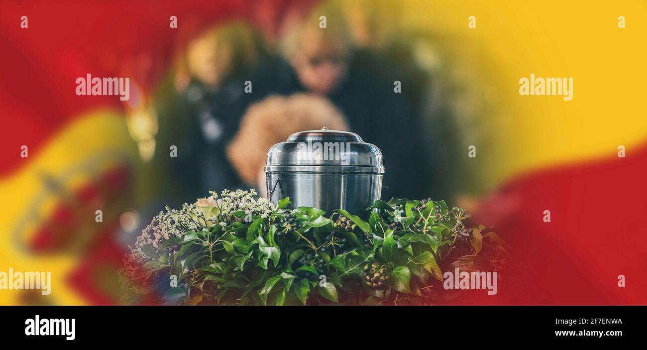 A metal urn with ashes of a dead person on a funeral, with people mourning in the background on a memorial service. Sad grieving moment at the end of Stock Photo