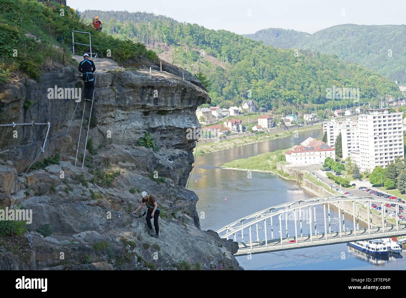 Decin, Czech Republic - May 7 2020: Two men friends climbing popular steep via ferrata route above river with harness and safety helmet, summer outdoo Stock Photo