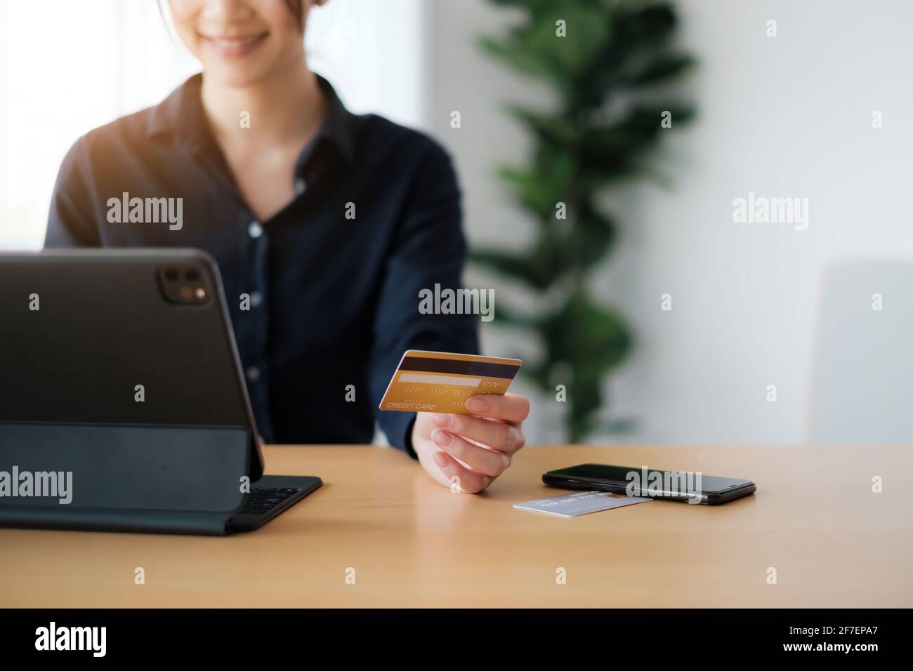 Woman in casual shirt paying with credit card online while making orders via application on tablet. Successful and happy business woman making Stock Photo