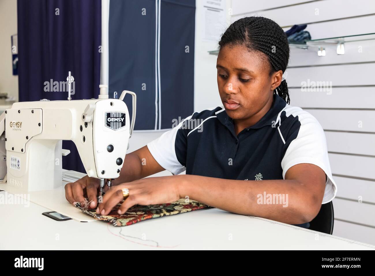 Johannesburg, South Africa October 2, 2012 Young African woman tailer repairing clothing on a