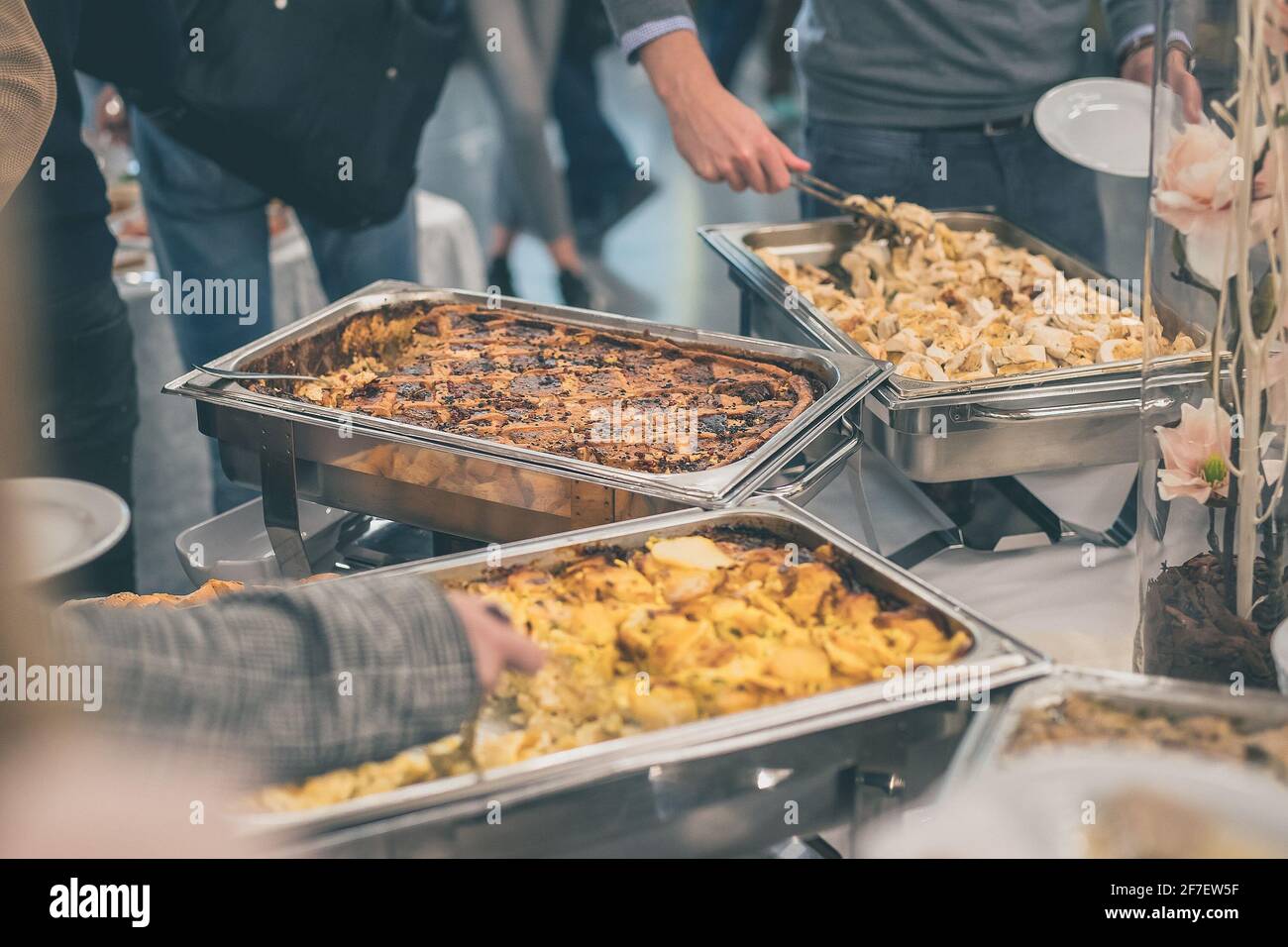 Hands of people seen taking food out of stainless steel containers at a  buffet or catering gala event. Tasty food being served on a catering event  Stock Photo - Alamy
