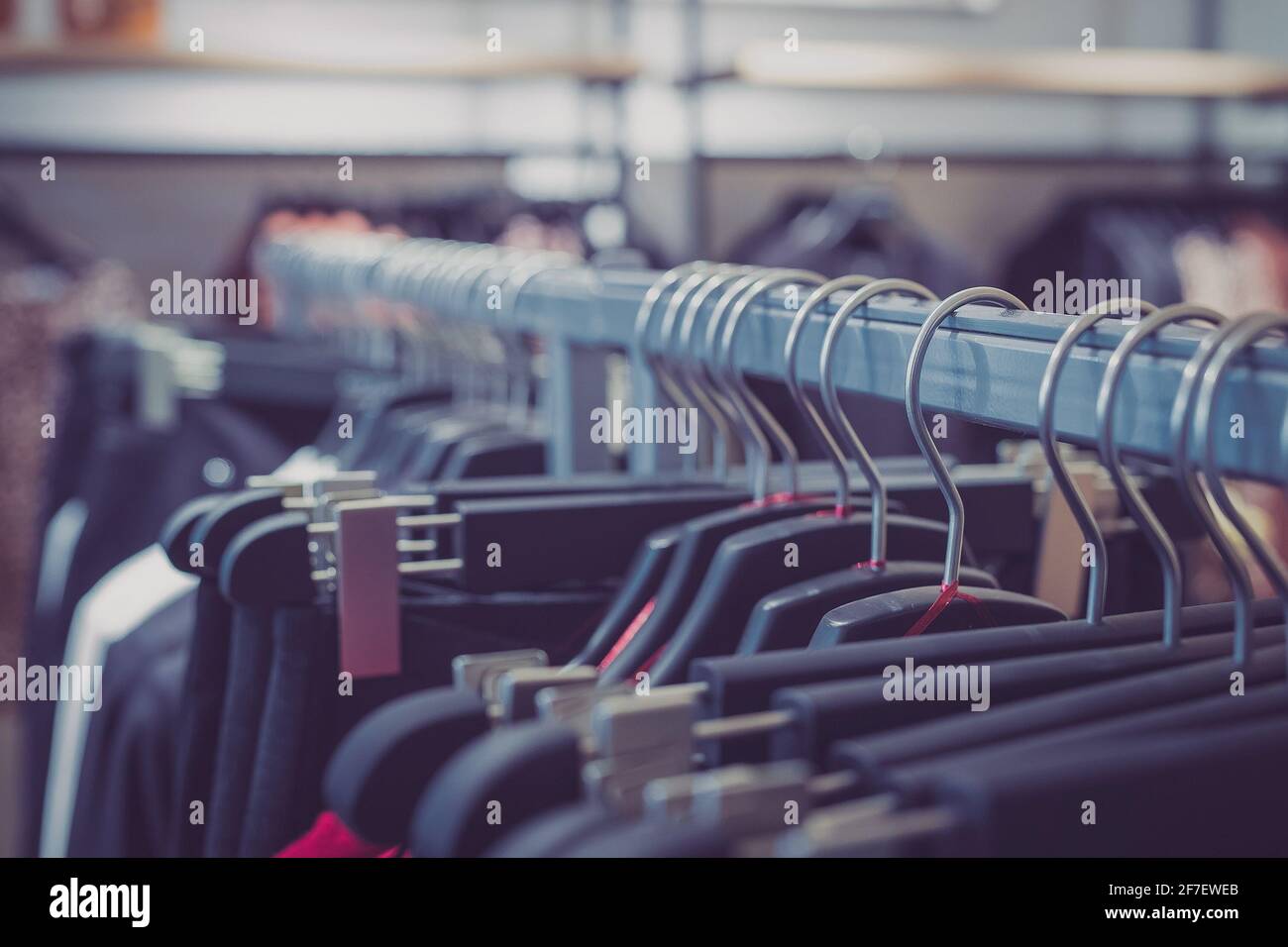 Row of many different clothes hanging on a hanger in a textile shop using classic wire and plastic hangers. Row of clothes in a shop. Stock Photo
