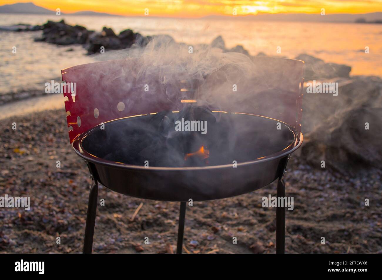 Grilling burgers on a small metal portable charcoal grill on the shores of  Lac Leman in Switzerland during early winter evening with sun setting down  Stock Photo - Alamy