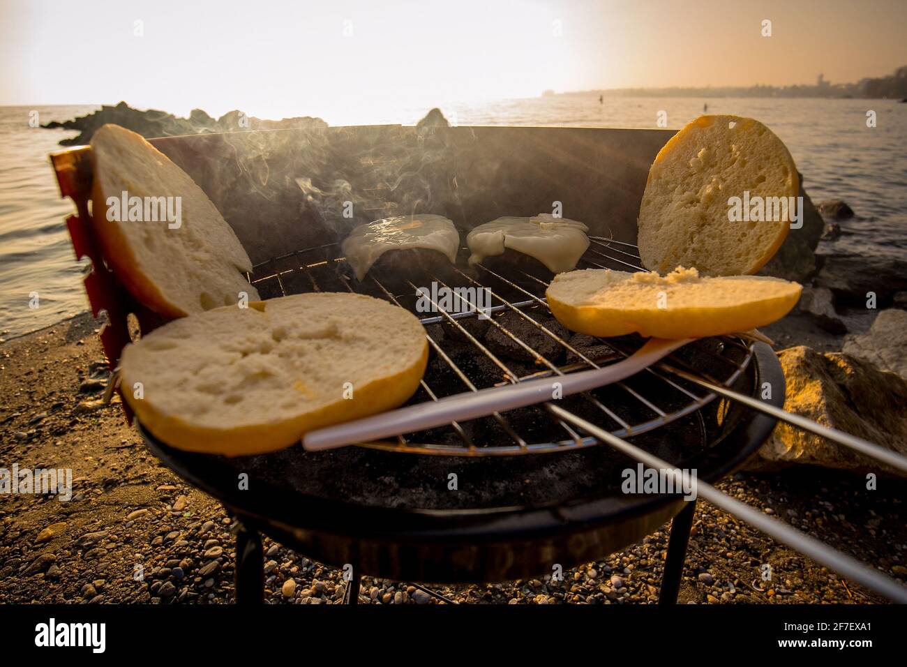 Grilling burgers on a small metal portable charcoal grill on the shores of  Lac Leman in Switzerland during early winter evening with sun setting down  Stock Photo - Alamy