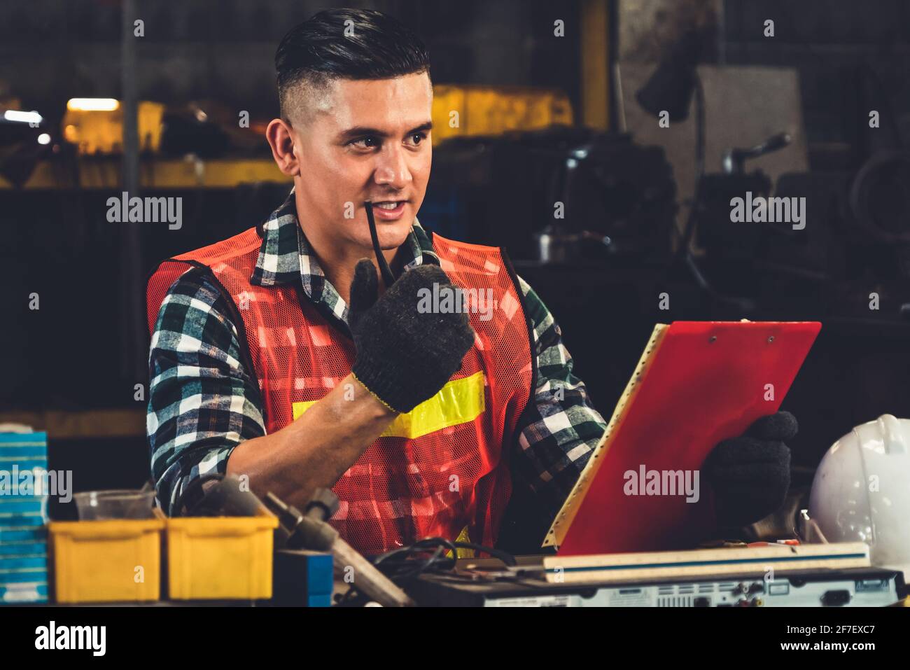 Factory worker talking on portable radio while inspecting machinery ...
