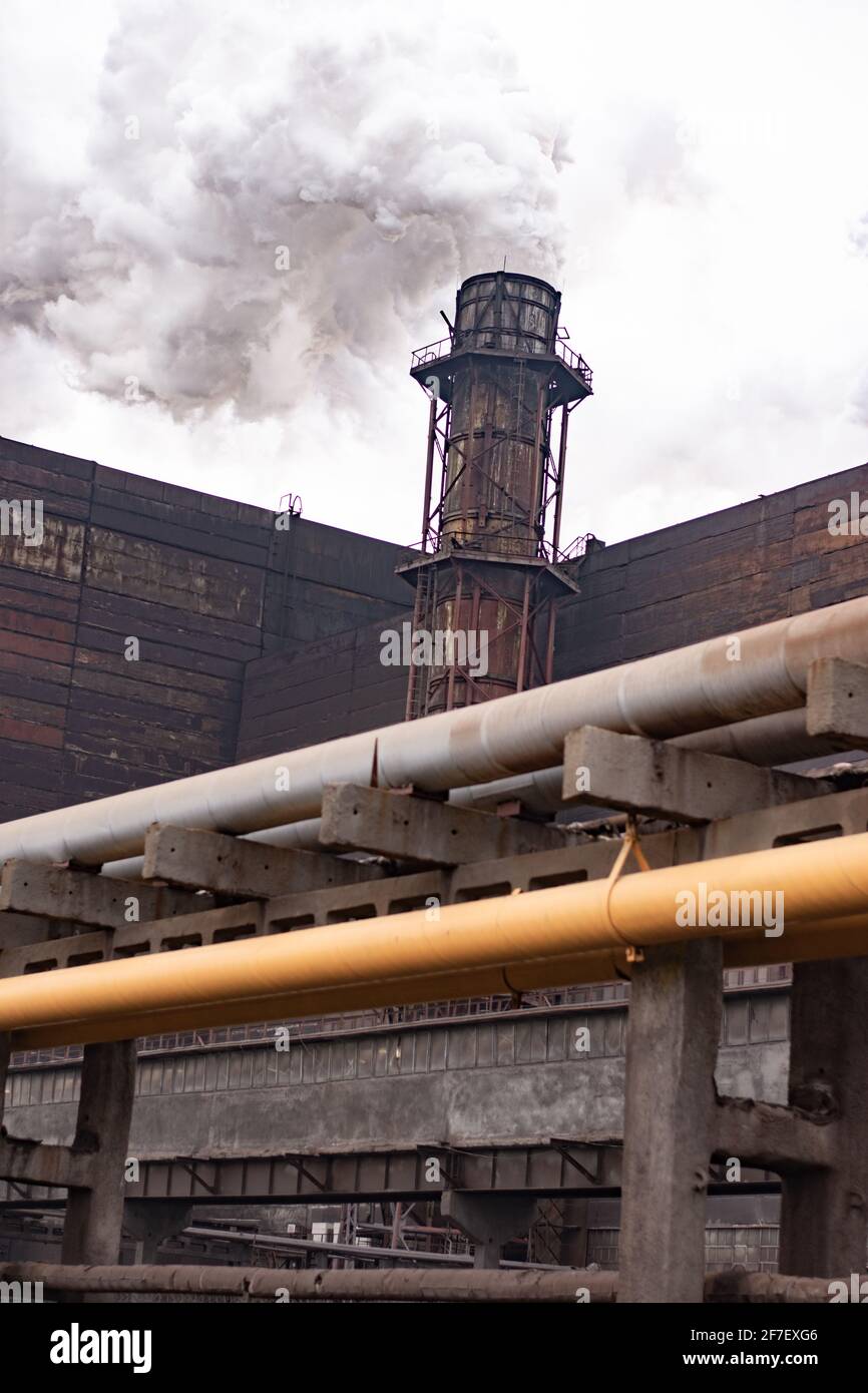 Plant pipes pollute atmosphere. Industrial factory pollution, smokestack exhaust gases. Stock Photo
