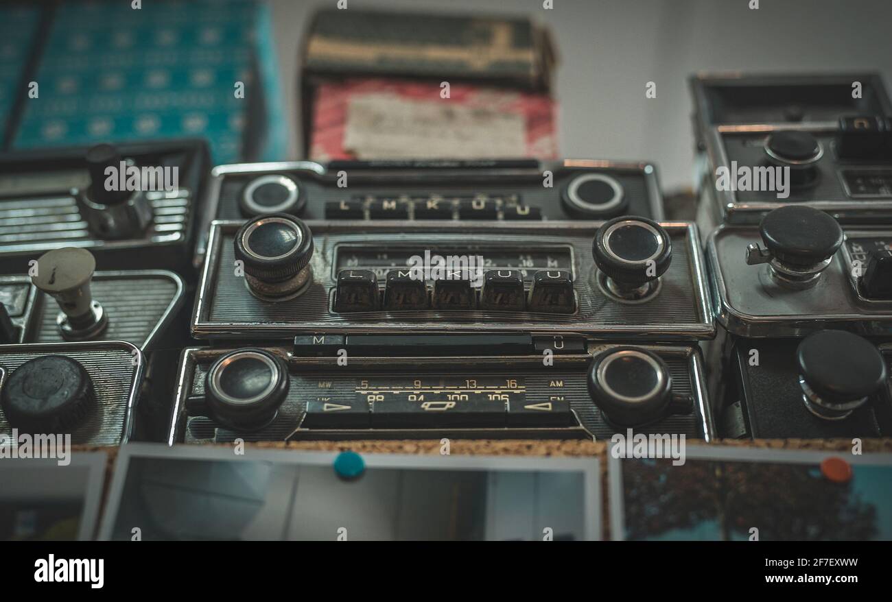 Vintage old timer radios stacked on a shelf. Flea market style collection of a retro car stereos. Stock Photo