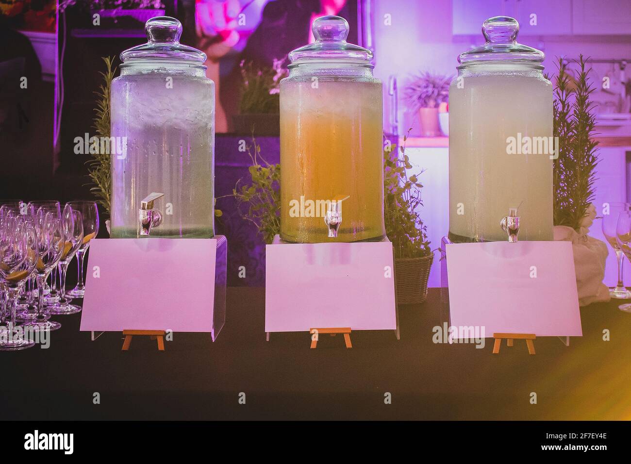 Big glass bottles or containers for drinks such as tea or water, lemonade or iced tea on an event or a gala party with empty signboards to write conte Stock Photo