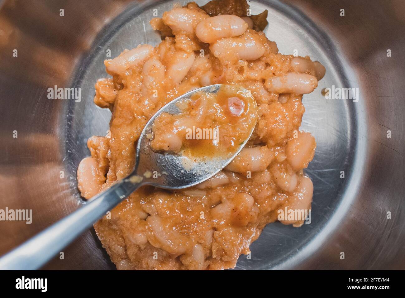 Traditional balkan food prebranac, beans, seen in a metal pot from above. Canned food preparation. Heating up a beans meal from a can. A spoon in food Stock Photo