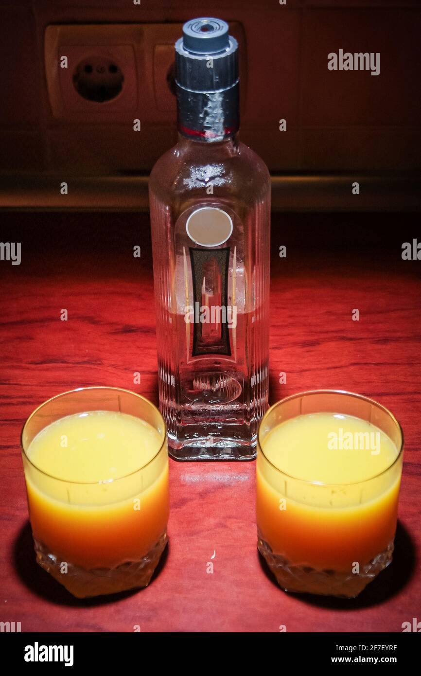 Glass bottle of Vodka on a red table with two glasses of vodka mixed