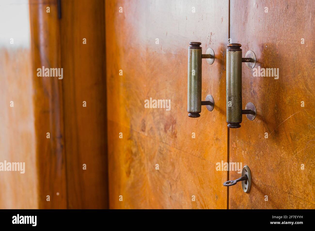 Old knob, lock and handles on an old wooden furniture. Visible also lock and a key on an old decayed wooden door Stock Photo