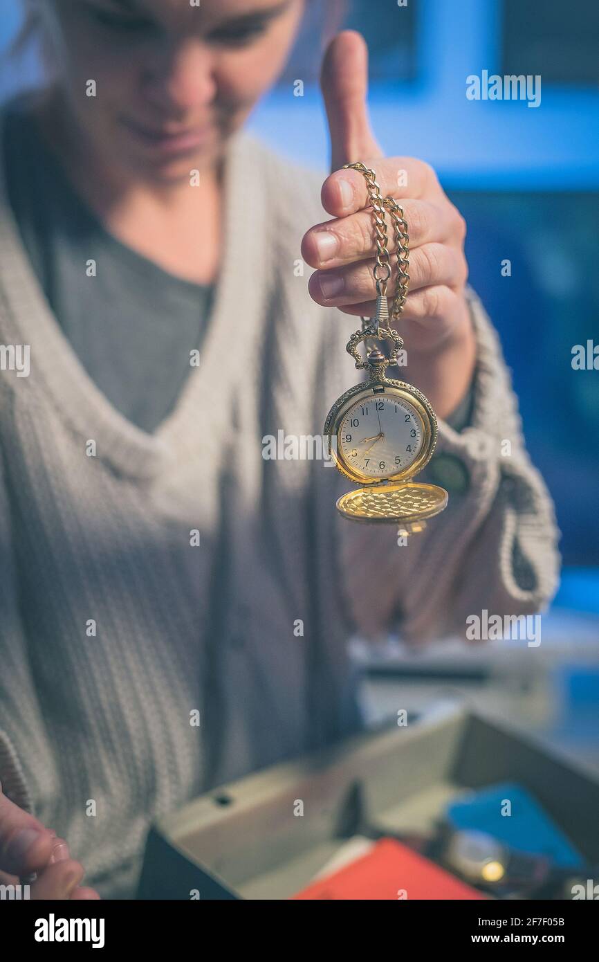 Woman discovering antiques like gold pocket watch and other valuables from a metal case during christmas or other festivities. Discovering heritage ob Stock Photo