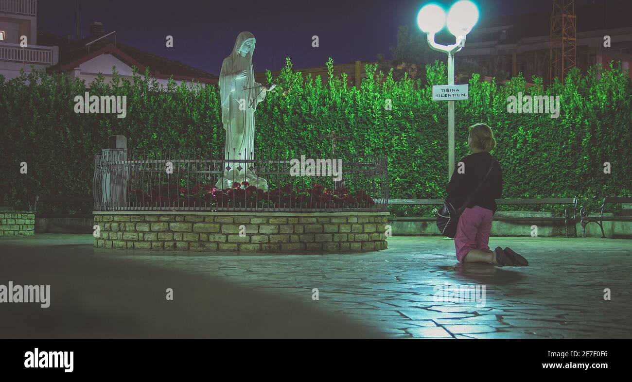 Unknown woman is praying in Medjugorje holy area during the night time. Stock Photo