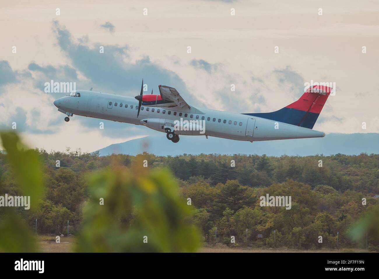 Propeller passenger aeroplane is taking off at Rijeka international airport n the cloudy and rainy day. Stock Photo