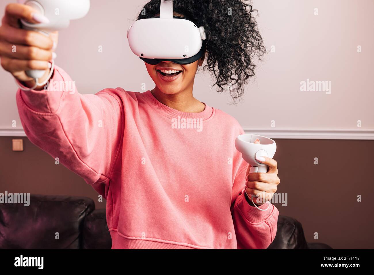 Young African American female in VR goggles and with joysticks experiencing augmented reality Stock Photo