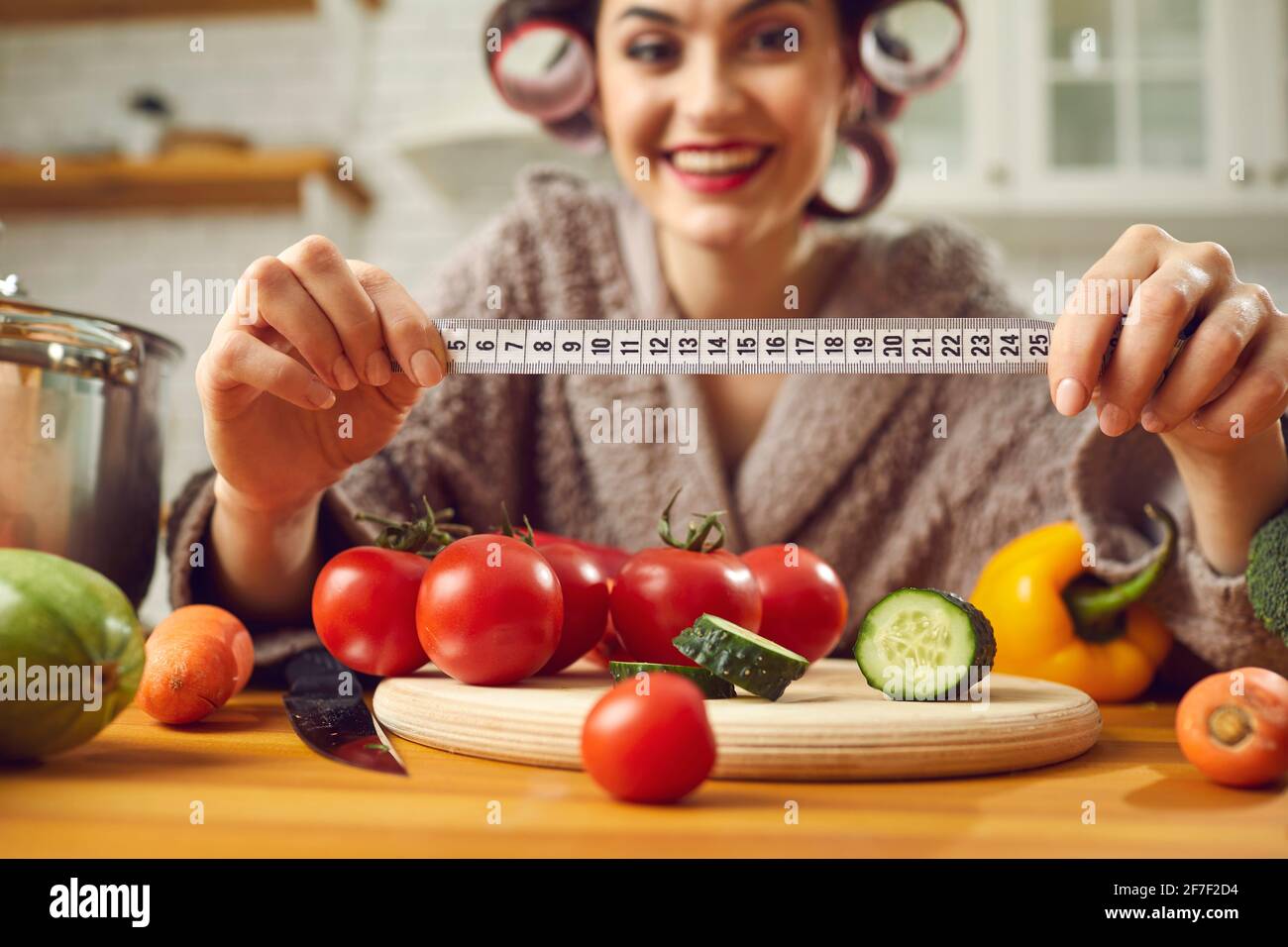 Measure tape in young woman housewife hand over fresh organic vegetables Stock Photo