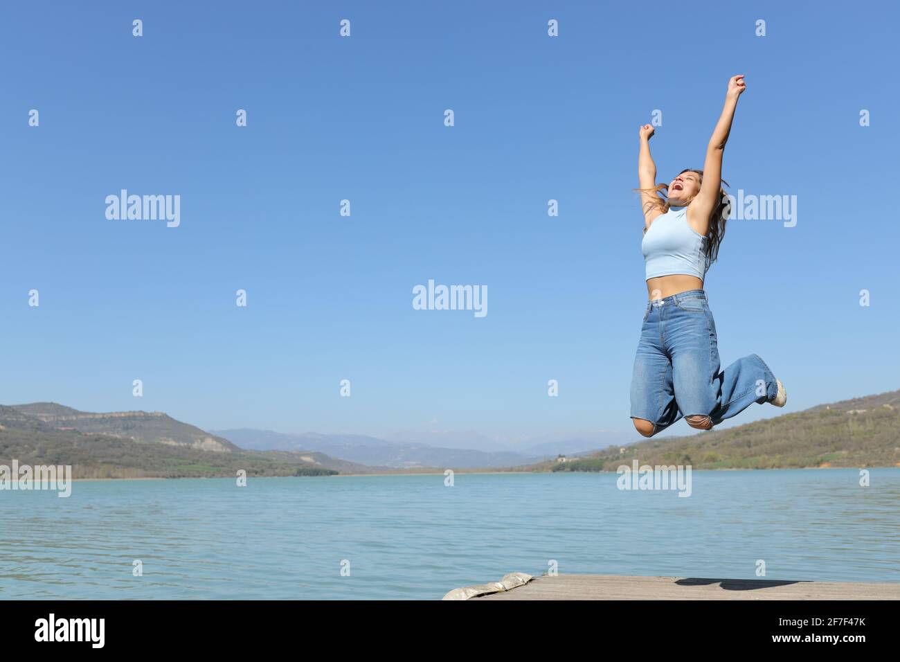 Happy woman jumping celebrating holiday in a lake on summer vacation Stock Photo