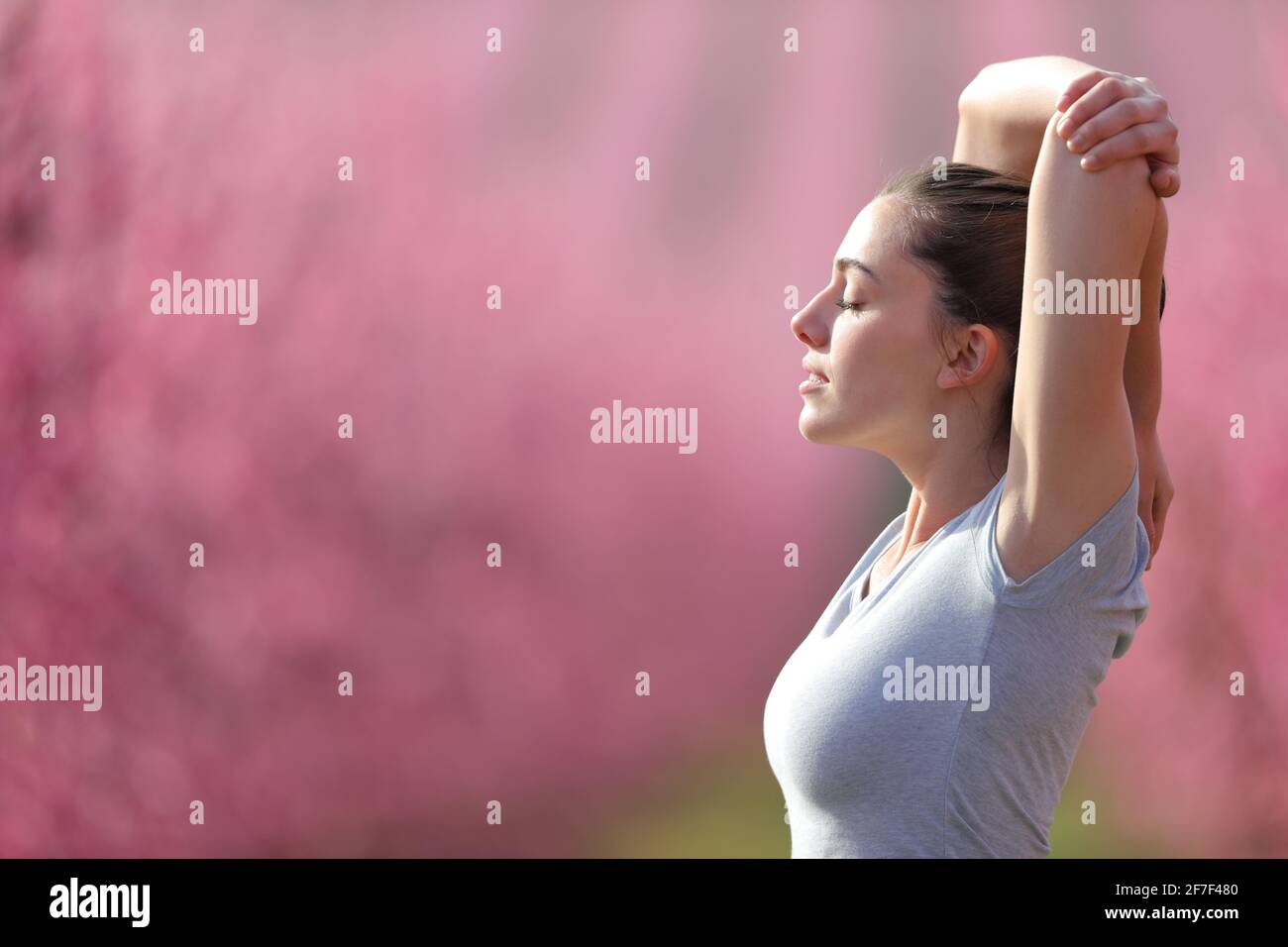 Side view portrait of a relaxed runner stretching arms in a field after run Stock Photo