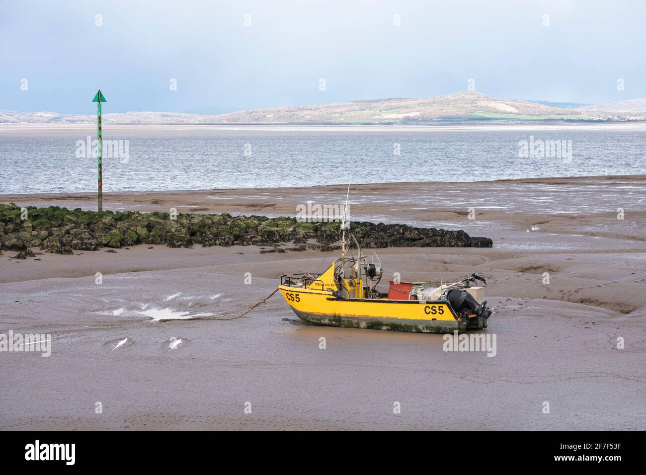 Small yellow fishing boat on the beach in Morecambe, Lancashire Stock Photo