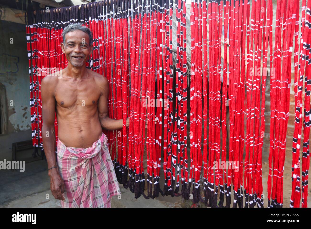 Sari making Artisan standing near colorful dyed threads in Muhulia Village of Cuttack district of Odisha, India Stock Photo