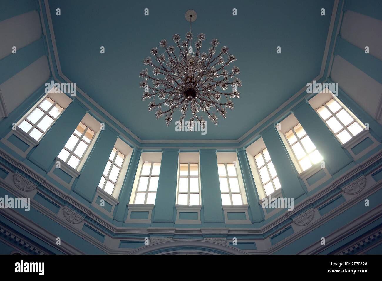 Bottom view of the big chandelier under blue ceiling in old classic building. Interior of waiting hall of the railway station Stock Photo