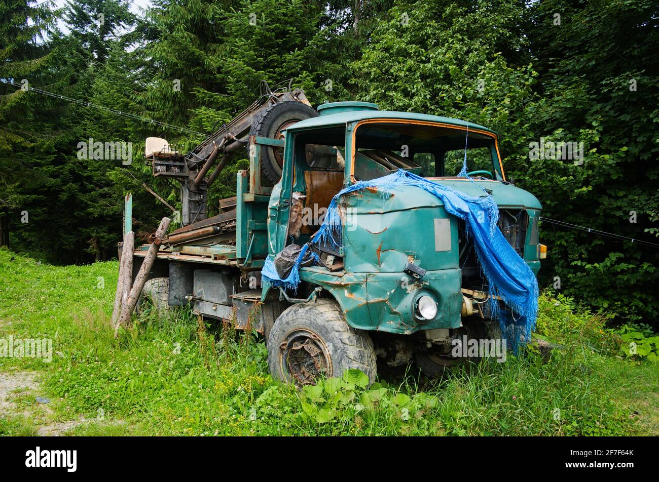 Old damaged car for transporting logs. Abandoned timber car in a village. Carpathian mountains, Ukraine. Stock Photo