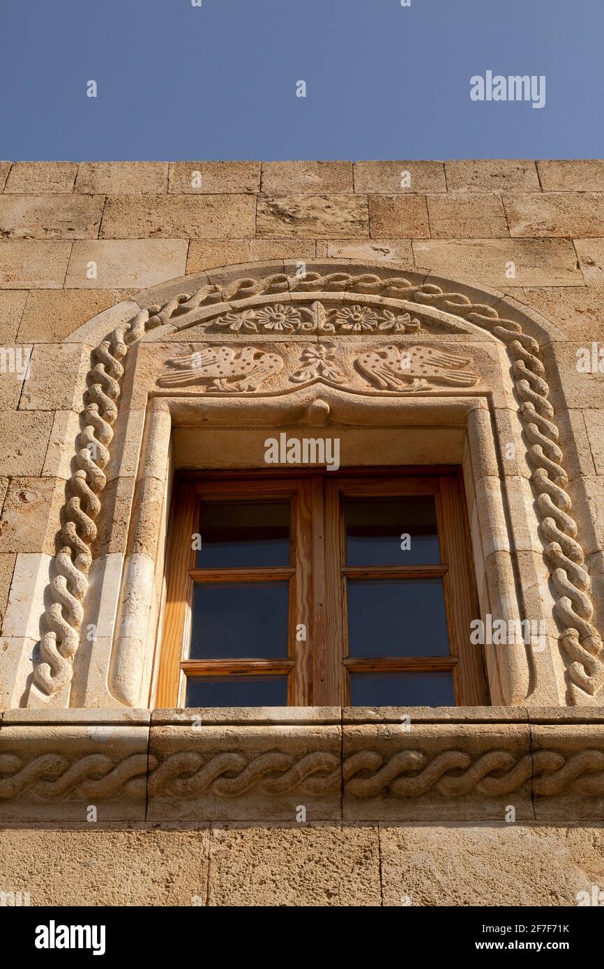 An ornately decorated windowframe in Lindos on Rhodes, Greece. Lindos has many stone-built properties known as captain's houses that were built for we Stock Photo