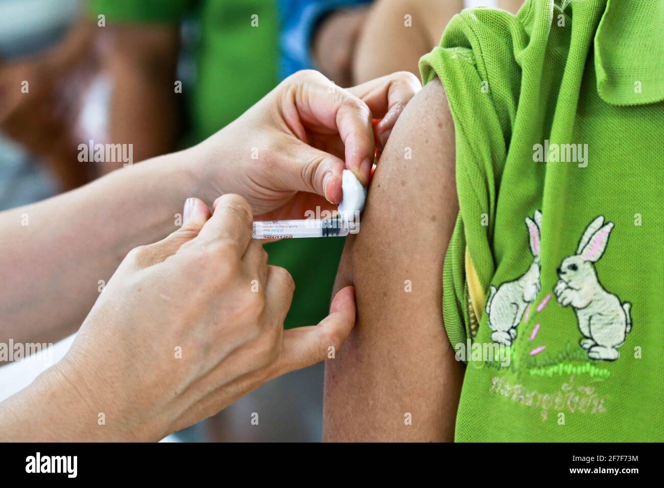 Doctor or nurse hands in medical white gloves using needle syringe drawing blood sample from patient arm in hospital. Stock Photo