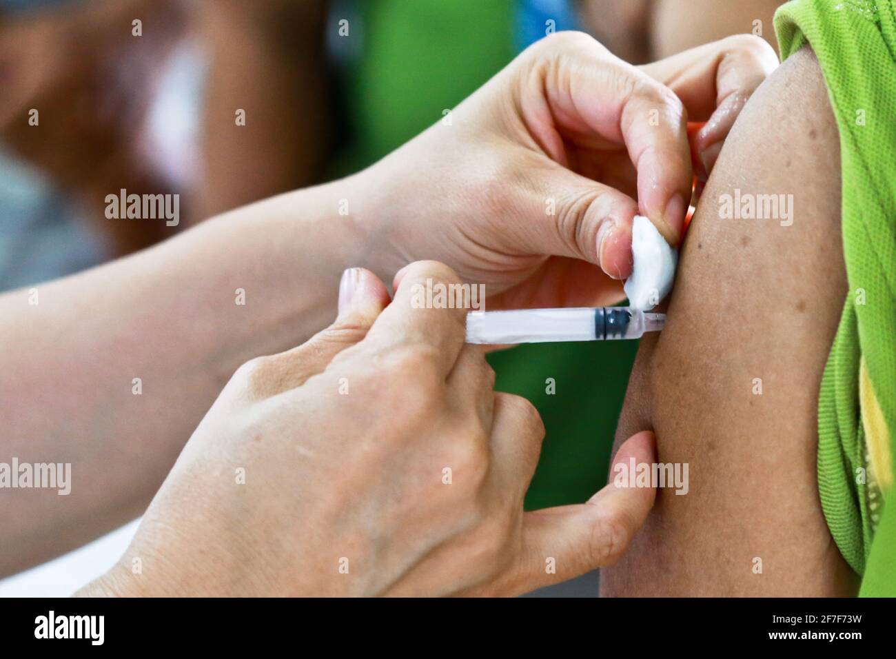 Doctor or nurse hands in medical white gloves using needle syringe drawing blood sample from patient arm in hospital. Stock Photo