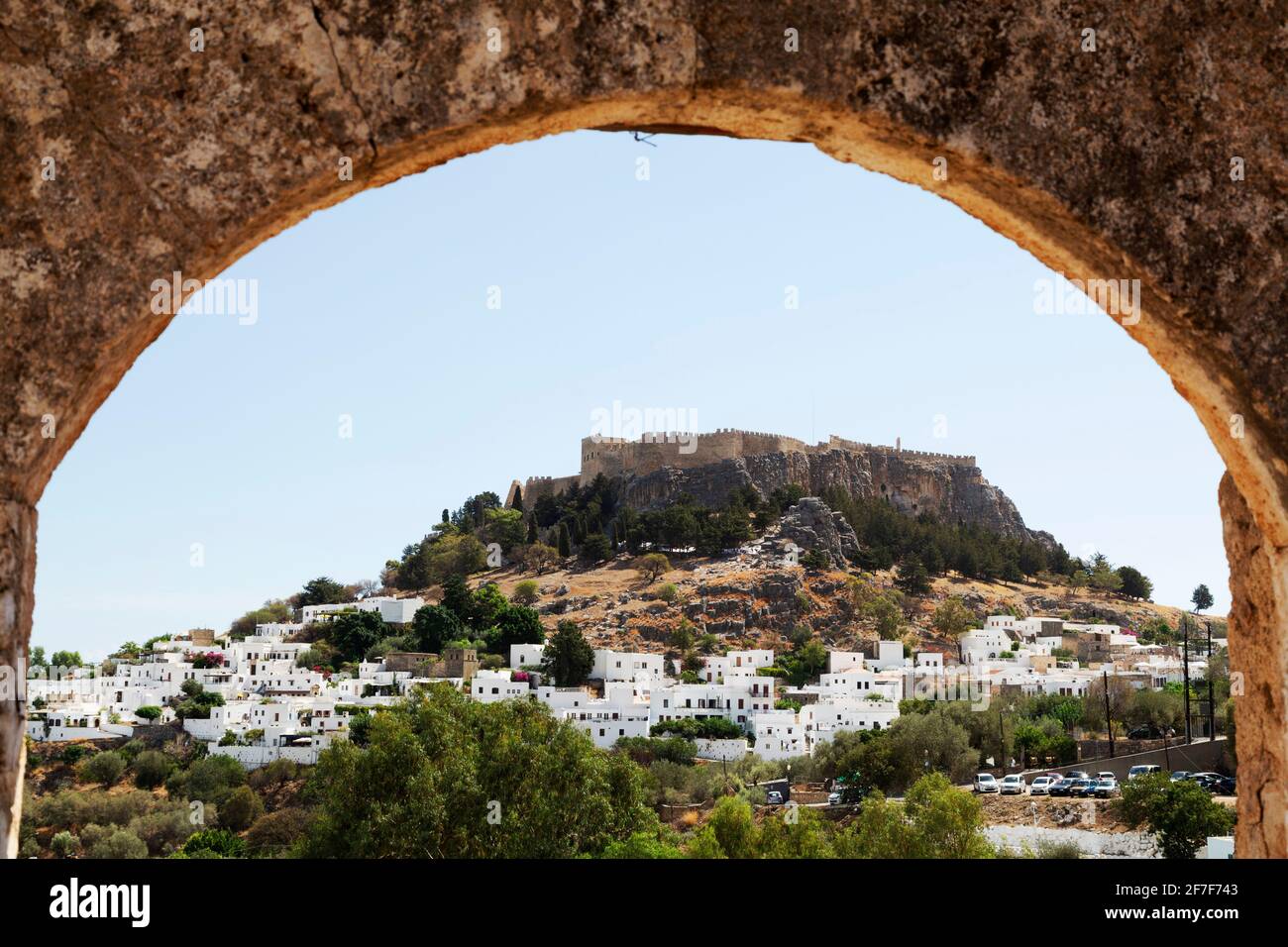 The Lindian Acropolis overlooking white houses in the fishing village of Lindos on Rhodes, Greece. The Ancient Greek citadel and place of worship is s Stock Photo