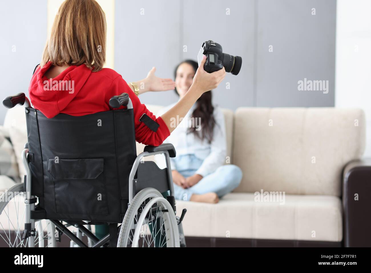 Woman in wheelchair with camera conducts home photo session Stock Photo