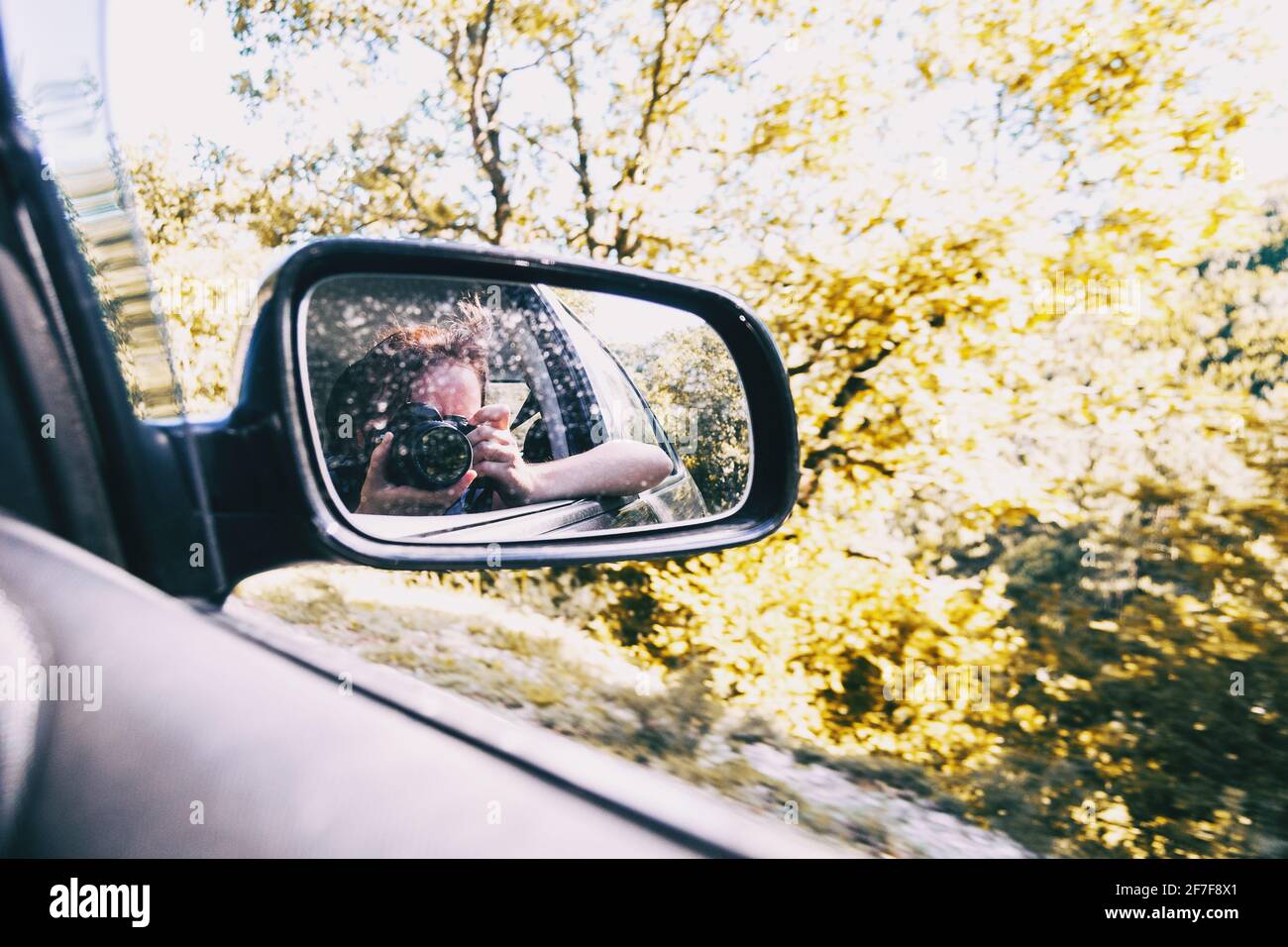 Selfie of a girl in the rear view of the car while the car is running. The girl wears her hair tied up and blows her away with the wind. Stock Photo