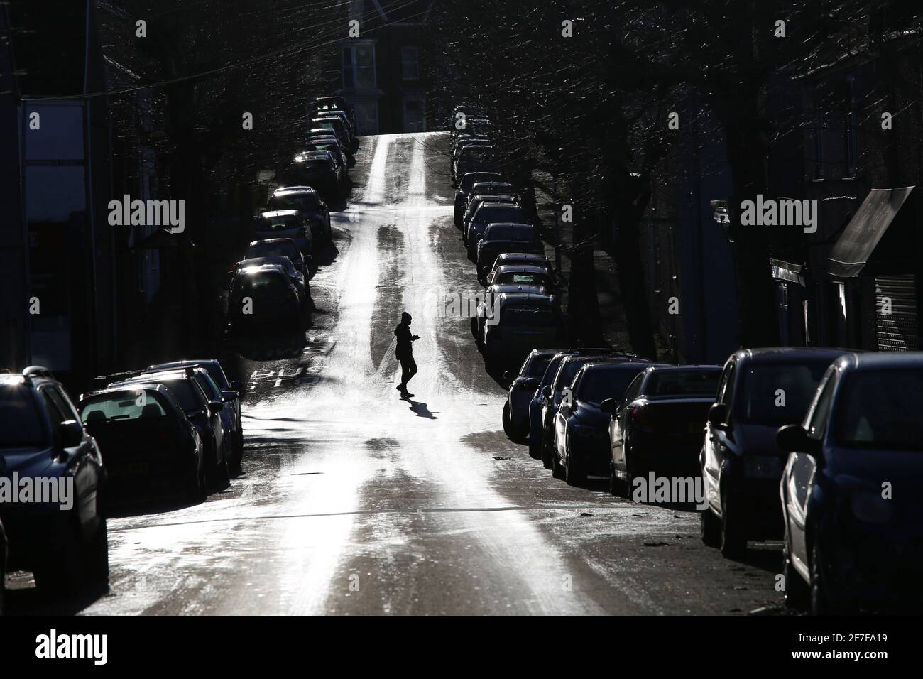 Swansea, Wales, UK - December 6, 2020, city street full of parked cars with pedestrian walking across the road, high contrast Stock Photo