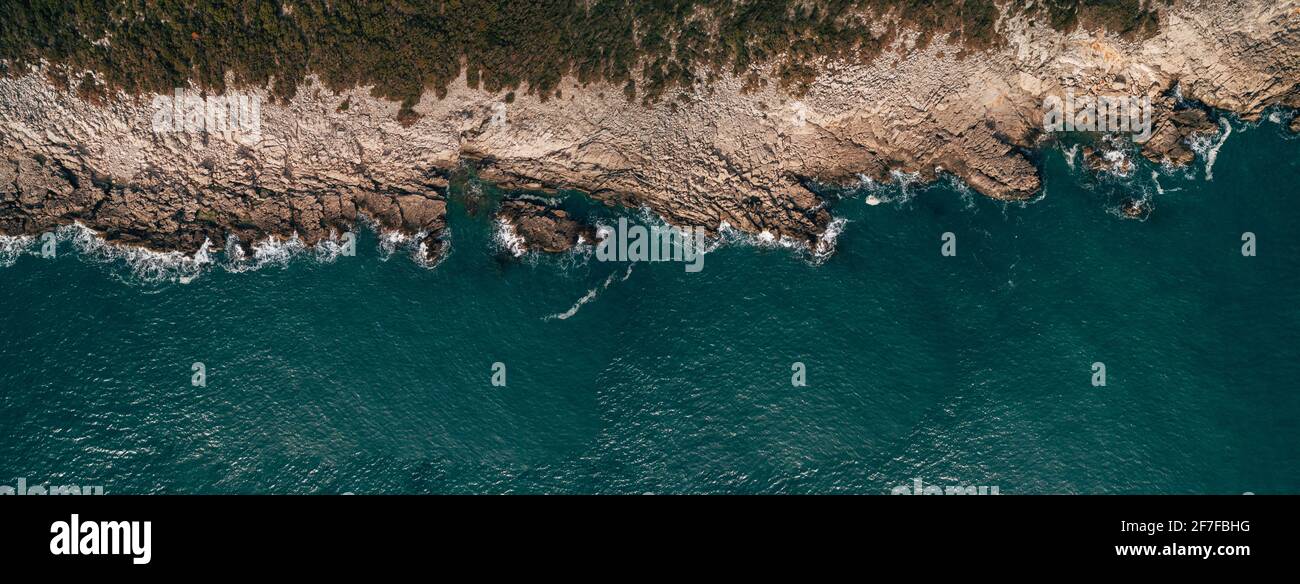 Aerial view of rocky beach and sea with transparent blue water at ...
