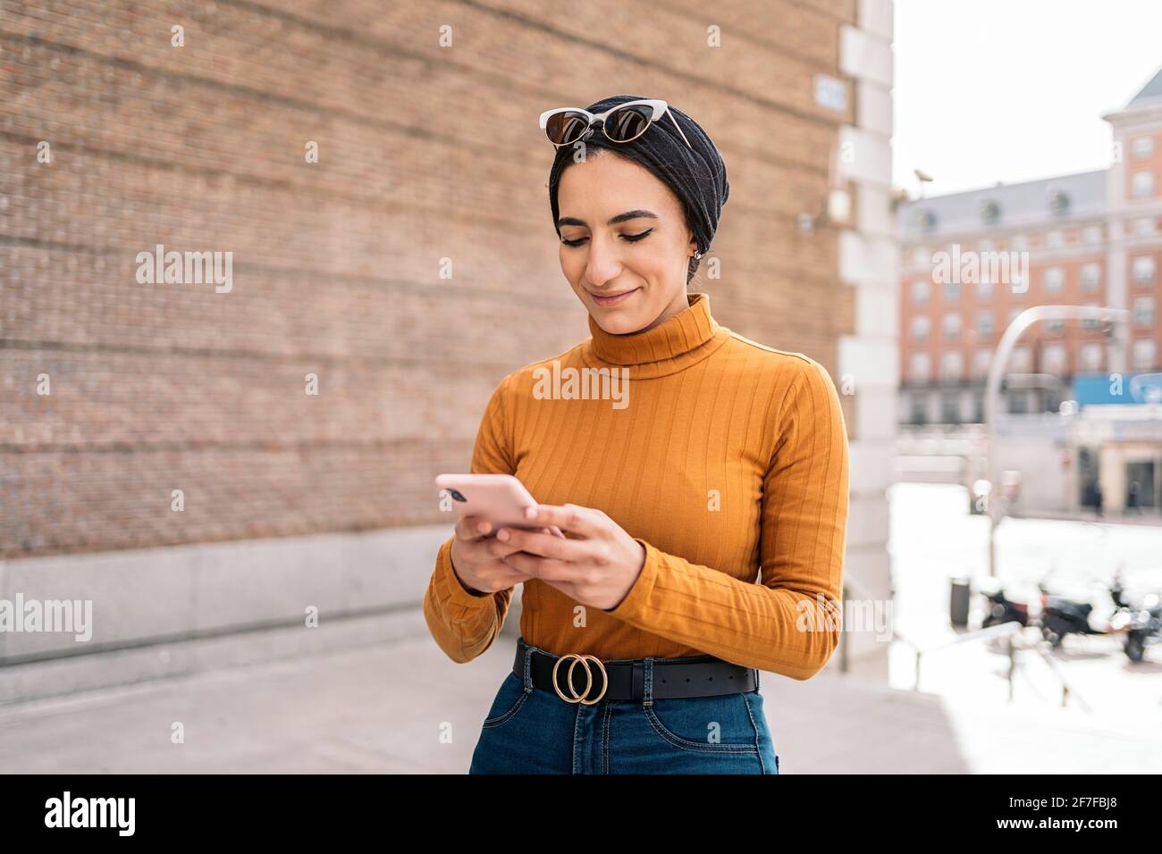 Pretty young muslim woman wearing head scarf using her mobile phone in ...