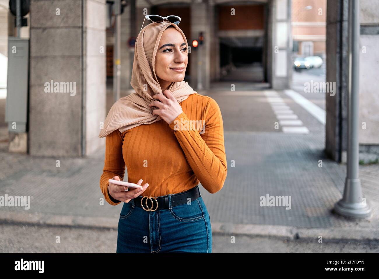 Pretty young muslim woman wearing head scarf using her mobile phone in ...