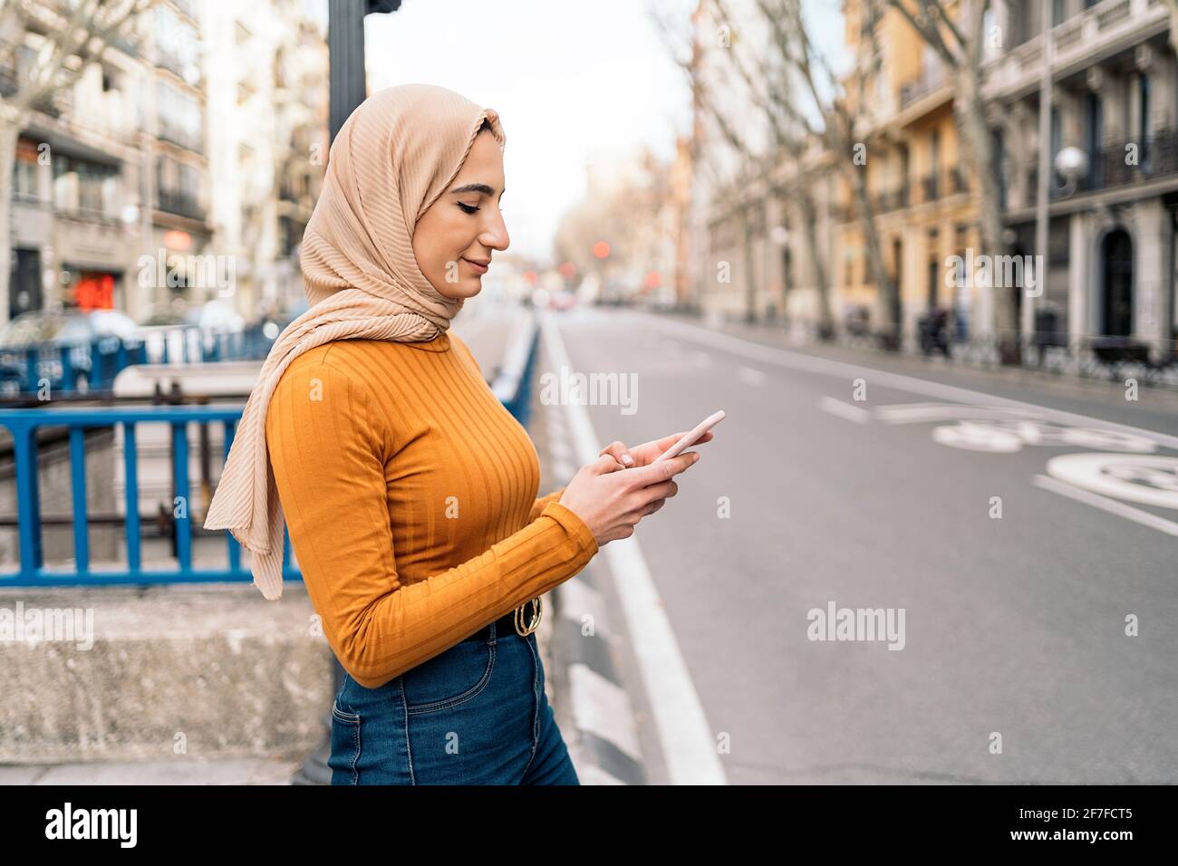 Pretty young muslim woman wearing head scarf using her mobile phone in ...