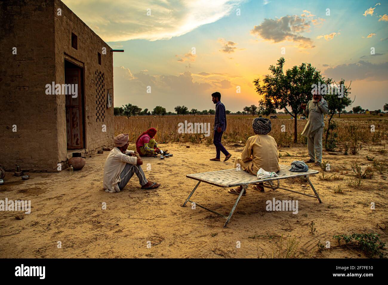 indian farmers family sit in the middle,taking a break in the field during harvesting crops.beautiful clouds in background. Stock Photo