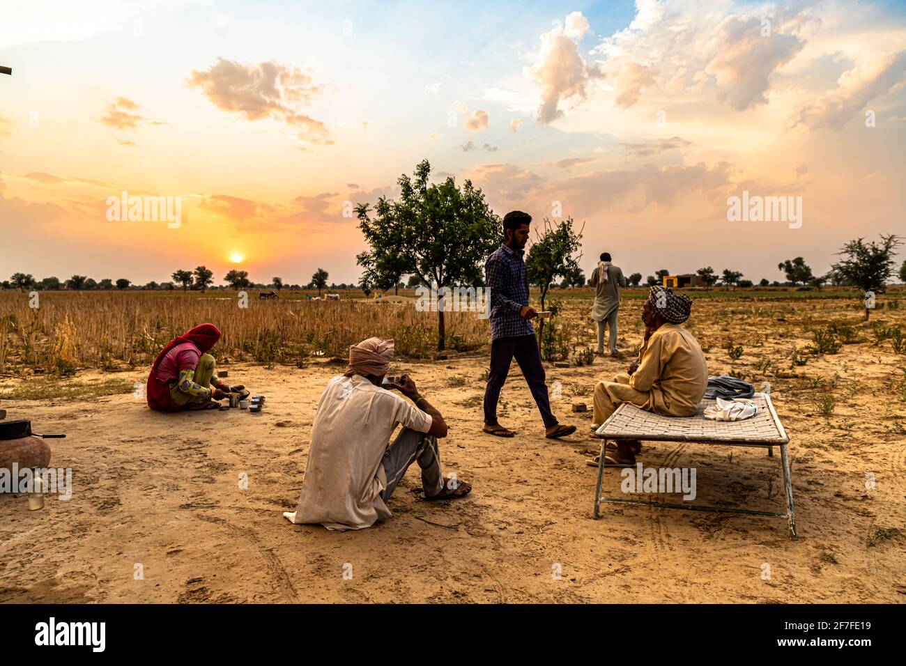 indian farmers family sit in the middle,taking a break in the field during harvesting crops.beautiful clouds in background. Stock Photo