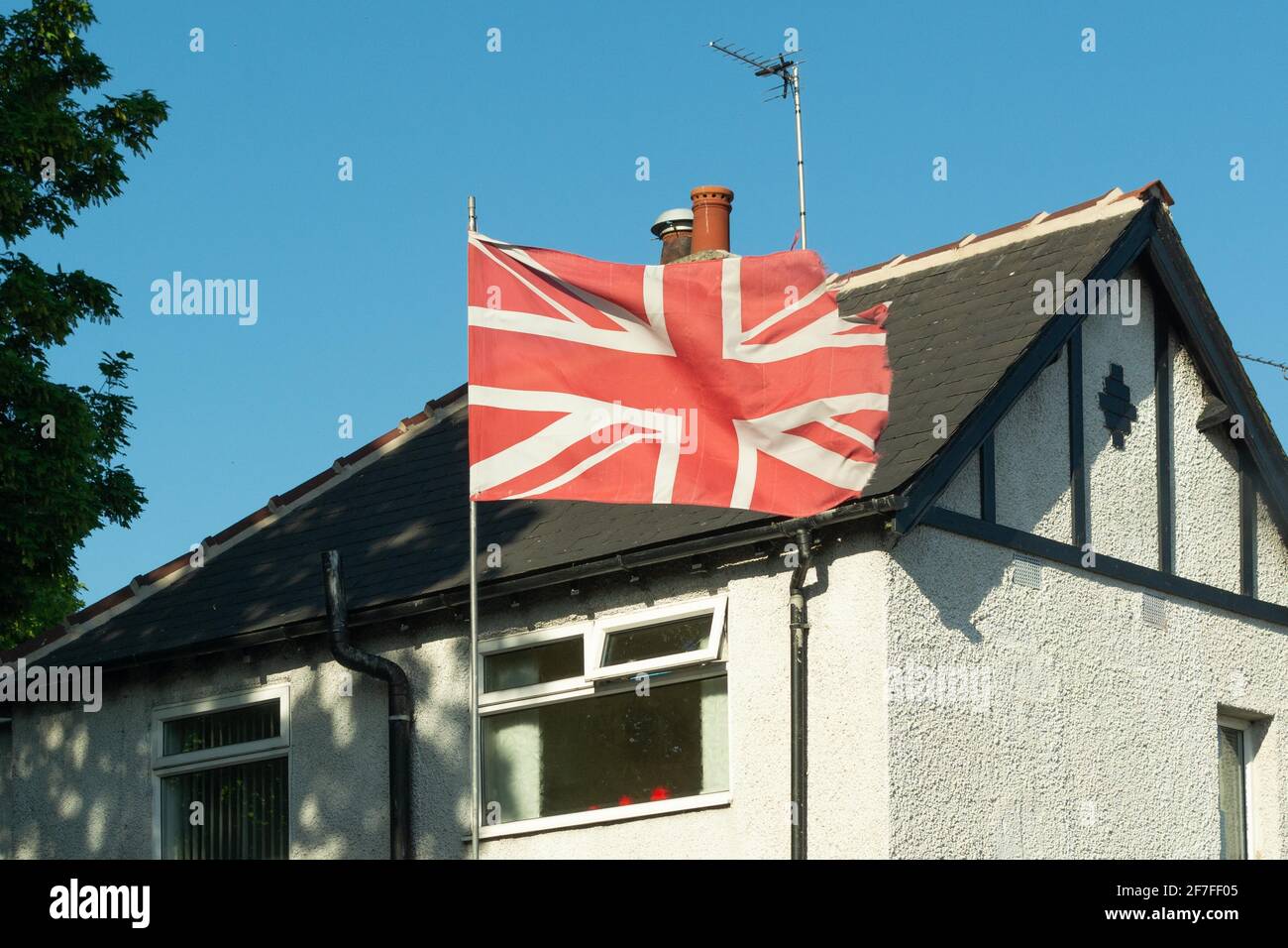 Red and white union jack flag flying outside house in England, UK Stock Photo