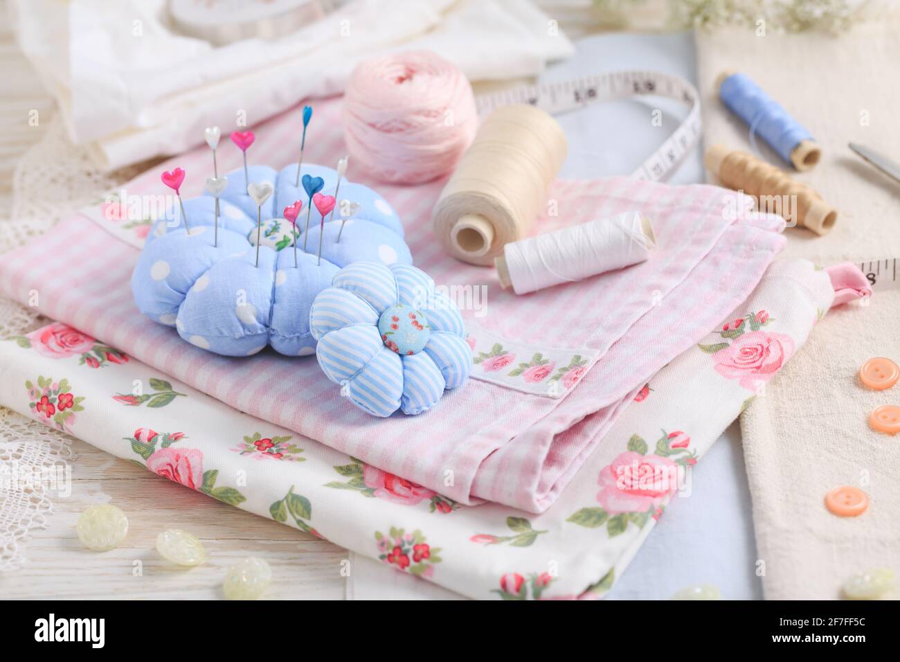 Sewing tools and supplies  - handmade pincushion, scissors, bobbins with thread, needles and fabric. Hobby, crafting, creativity, free time at home co Stock Photo