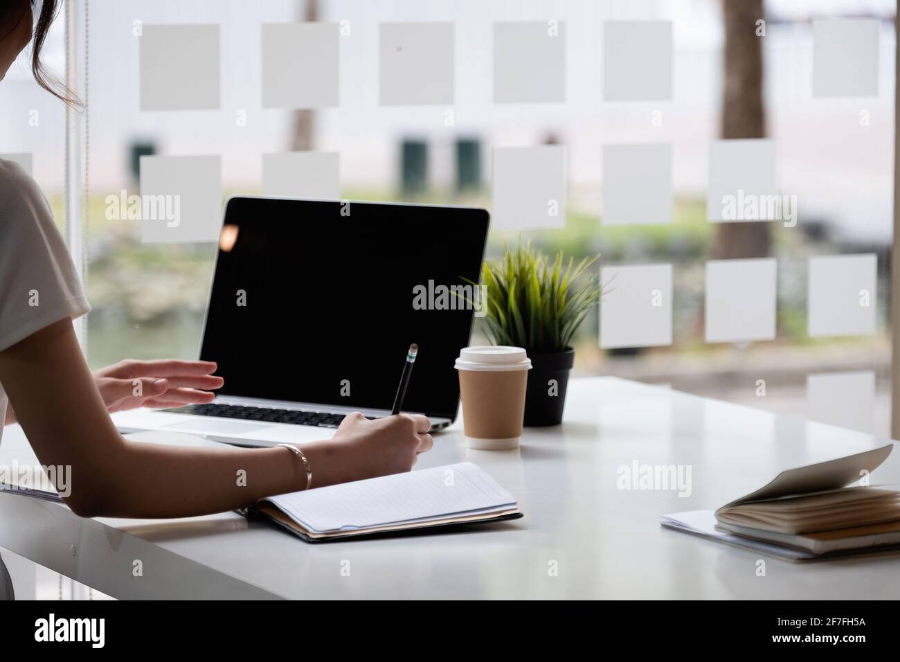 Close up of hand businesswoman writing on paper and using laptop to searching data for working or online learning Stock Photo