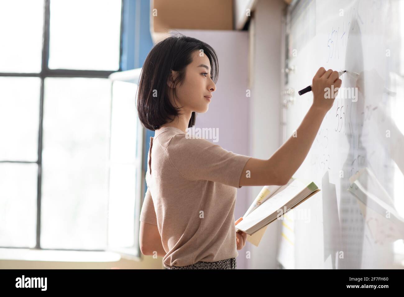 Young teacher writing on blackboard Stock Photo