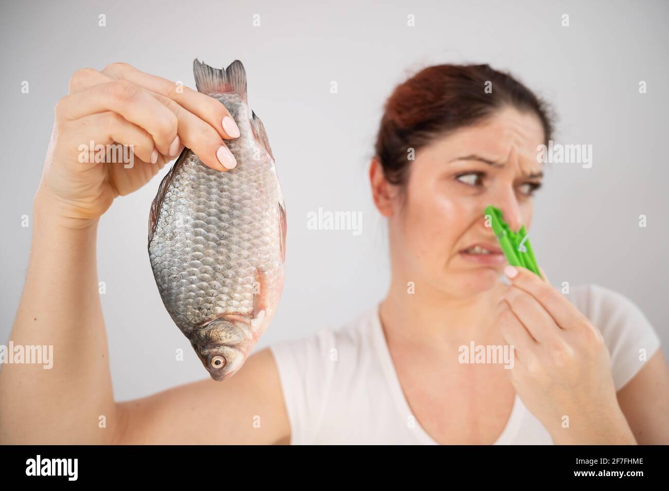 Caucasian woman with a clothespin on her nose because of the disgusting smell of fish. A