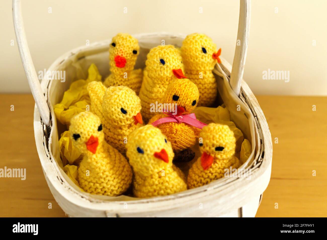 Cute knitted chicks containing chocolate eggs in an Easter basket Stock Photo