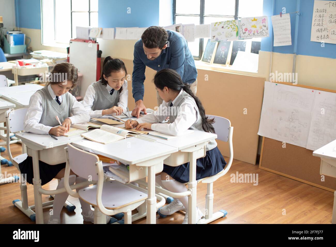 Young teacher helping students in classroom Stock Photo