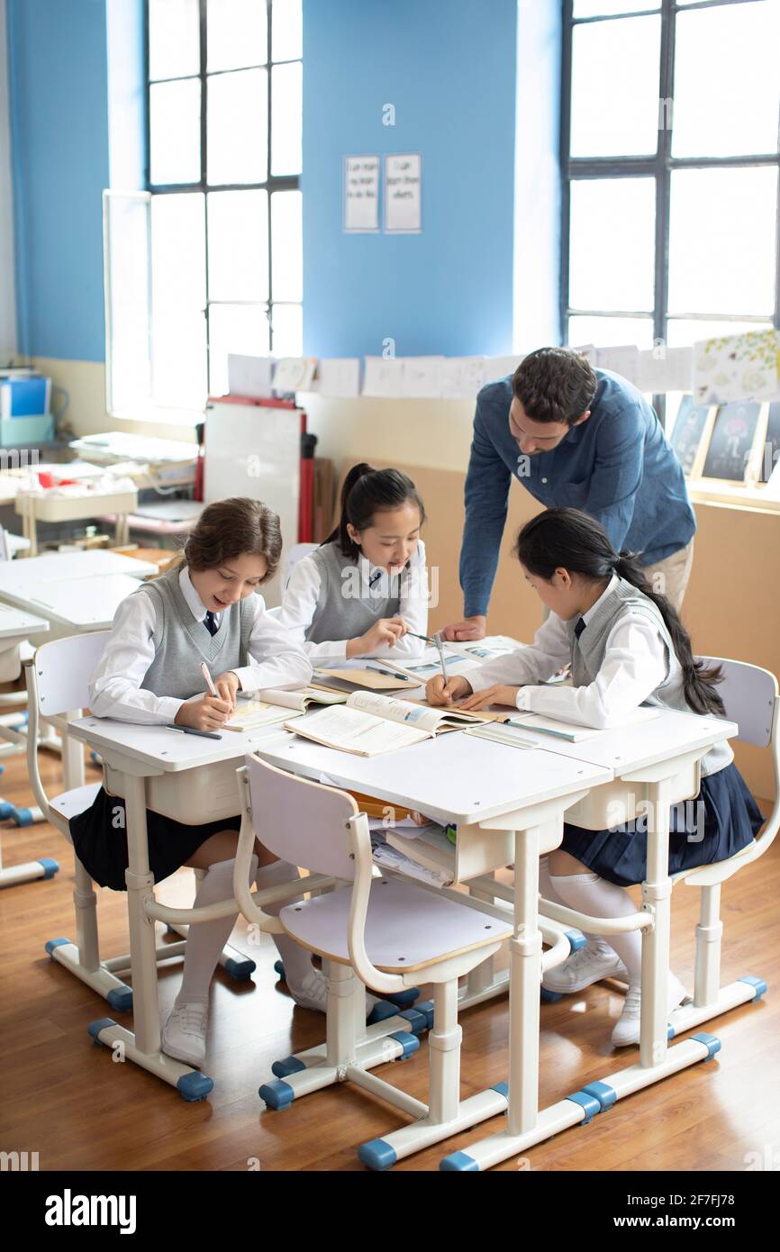 Young teacher helping students in classroom Stock Photo