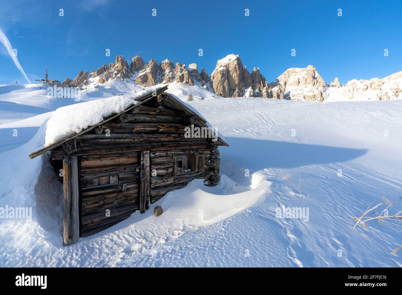 Isolated wooden hut covered with snow with Cir Group peaks in background at sunset, Passo Gardena, Dolomites, South Tyrol, Italy, Europe Stock Photo