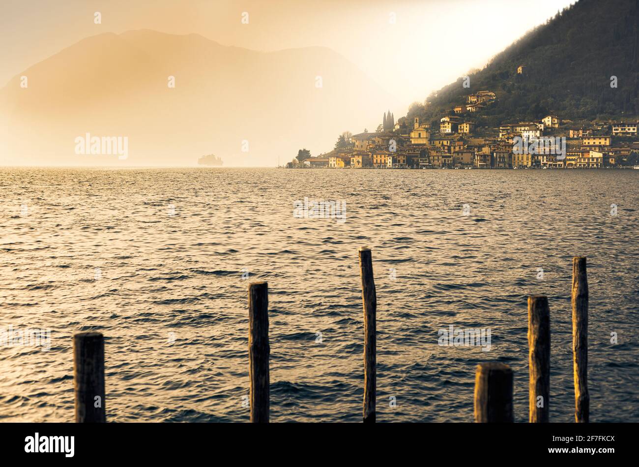 Light in the fog illuminates Peschiera Maraglio village, Monte Isola, Lake Iseo, Brescia province, Lombardy, Italian Lakes, Italy, Europe Stock Photo