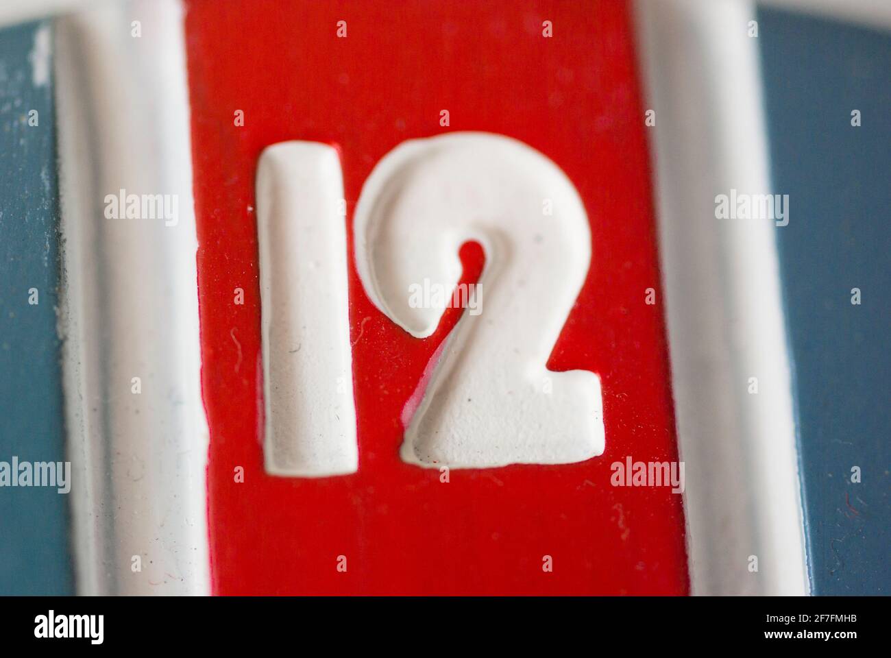 A close up of the number Twelve / 12 at the top of a red white and blue clock face, Stock Photo